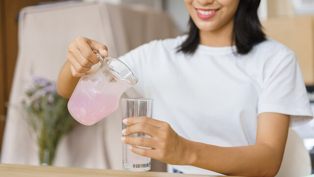 Cozy lifestyle concept, Young woman pour water from jug into glass while having snack at home