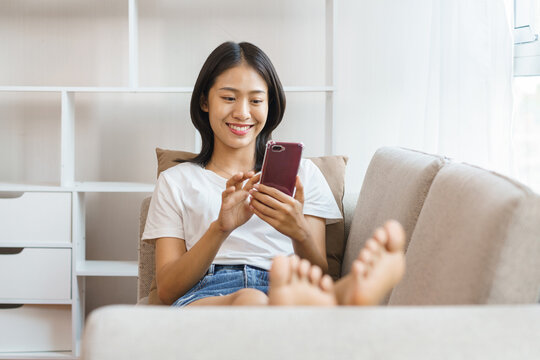 Home lifestyle concept, Young woman lying on couch and use smartphone to surf social media at home