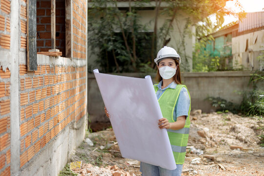 engineer concept The female engineer wearing a white mask and helmet holding her proposal paper of the construction