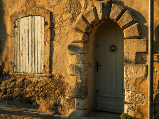 front door and window with closed shutters in an ancient stone house in Provence, France