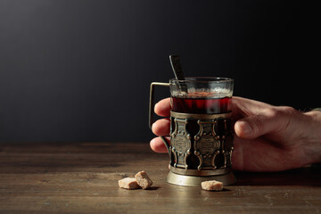 Man hand holds a traditional Russian glass holder with hot tea.