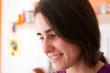 An attractive young girl looking to the side, smiling in the house.