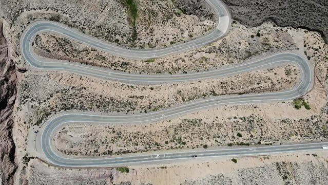 Aerial Top View Of The Winding Road With Several Hairpin Turns And Driving Vehicles