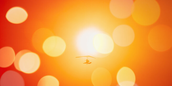 Motorized Hang Glider Flying In Clear Sunny Sunset Sky With Sun On Background. panorama panoramic view