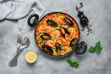 Traditional Spanish paella with seafood in a frying pan. Gray concrete grunge background. Top view, flat lay. Mediterranean food. Paella with prawns and mussels.