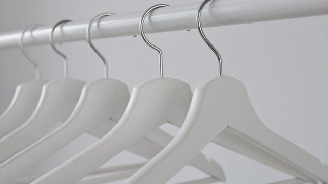White empty wooden clothes hangers on white wall background. Concept of sale in the store, discounts, minimalistic advertising. Fashion, stylish metal hook hangers. Equipment for home, shop, boutique