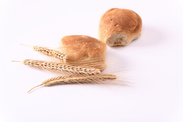 Freshly baked buns and ears of wheat on white background.