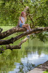 Fototapeta na wymiar Little girl with long hair posing in the park near the lake