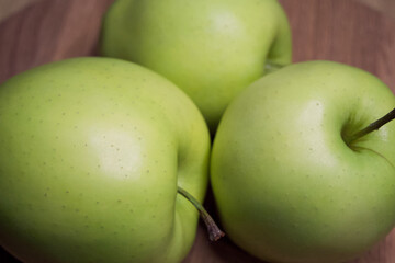 Three apples of cultivar Gold on a wooden surface, a close-up shot.