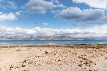 Fototapeta na wymiar Exotic view of the sinkhole area of the Dead Sea on a stormy winter day. PhotoStorm and rain at the Dead Sea coastline. Salt crystals at sunset. The texture of the Dead sea. Salty seashore. High
