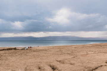 Exotic view of the sinkhole area of the Dead Sea on a stormy winter day. PhotoStorm and rain at the Dead Sea coastline. Salt crystals at sunset. The texture of the Dead sea. Salty seashore. High