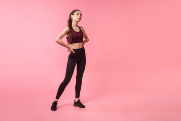 Fototapeta na wymiar Fitness model in sporty outfit posing on pink background