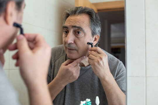 senior man shaving in front of the mirror