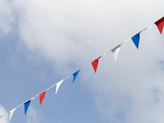 Photo of red white and blue triangular bunting on sky background. Queen's Jubilee 2022.