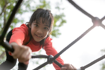 Cute little girl toddler having fun on the playground, climbing and sliding down