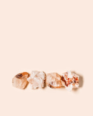 Flat lay bright beige quartz crystals on peach color background. Magic and healing crystal, gem stone, alternative medicine concept. Top view natural gemstone rock, quartz mineral