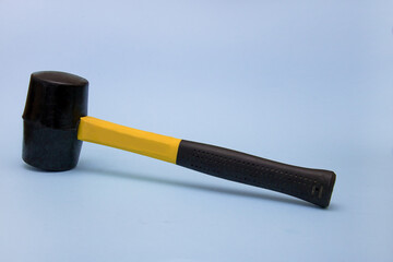 hammer with a black and yellow handle on a light blue background, the concept of construction, tools, repair, brutality