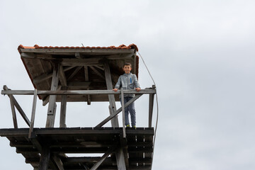 Happy boy with morning view of the spring forest landscape. Sunrise and view of the forest rescuer's observation tower, Goc mountain Serbia.