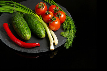 Vegetable set for salad. Red tomatoes and green young onions with cucumber on a plate