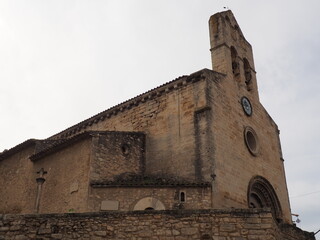 vista lateral de la iglesia de san juan bautista de vinaixa, estilo románico, campanario de espadaña, puerta de acceso con arquivoltas, arco medio punto y capiteles con motivos vegetales,´lérida, espa