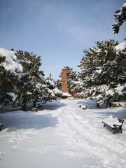 A snowy way to the monument tower between the trees in the outdoor park in Erzurum,Turkey 
