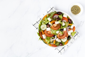 Fresh Greek salad with olives, tomatoes, cucumber and feta cheese on white background, copy space