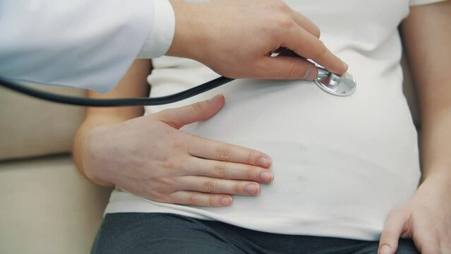 4k video of cropped view of pregnant woman stomach and hand with stethoscope.