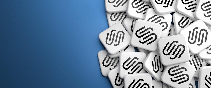 Logos of the cloud based Web Content Management System Squarespace on a heap on a table. Copy space. Web banner format.