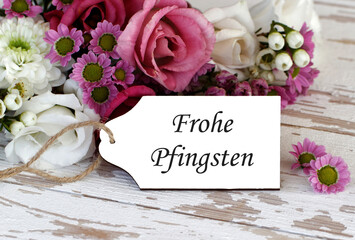 Label mit dem Text schöne Pfingsten vor einem Blumenstrauß.