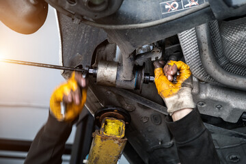 Closeup male tehnician mechanic greasy hands in gloves install new car oem suspensiom arm bushing...