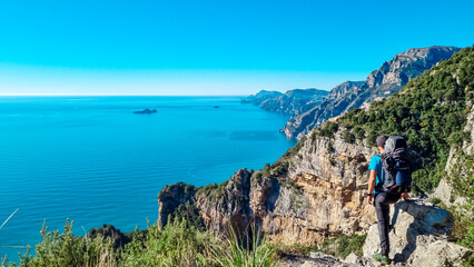 Fototapeta na wymiar Man with panoramic view from hiking trail Path of Gods between coastal towns Positano and Praiano. Trekking in Lattari Mountains, Apennines, Amalfi Coast, Campania, Italy, Europe. Mediterranean Sea