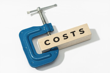 Costs squeeze concept. Clamp clamping down of a wooden block with text on white background