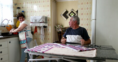 Happy senior commemorating good news on cellphone. Married couple at home kitchen celebrating