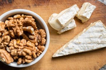 Fototapeta na wymiar Portion of Brie cheese with walnuts. Top view