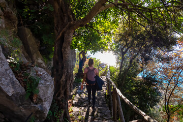 Obraz premium Active woman with backpack walking on hiking trail Path of Gods between Positano and Praiano, Amalfi Coast, Campania, Italy, Europe. Trekking through dense forest at Mediterranean Sea