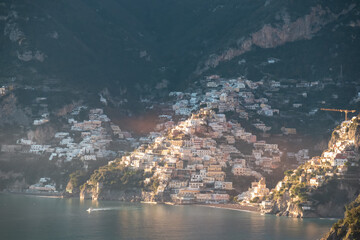 Panoramic view during sunset from Praiano to the coastal town Positano, Amalfi Coast, Campania, Italy, Europe. Looking at colorful houses at coastline of Mediterranean Sea at golden hour before sunset