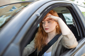 Fototapeta na wymiar Nervous female driver sits at wheel, has worried expression as afraids to drive car by herself for first time. Frightened woman has car accident on road. People, driving, problems with transport