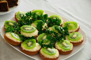 sandwiches with kiwi and grated cheese. healthy food concept. light breakfast illustration. holiday snacks in a white plate.