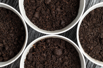 Potted soil with peat in metal pots. Growing greens or flowers at home concept.