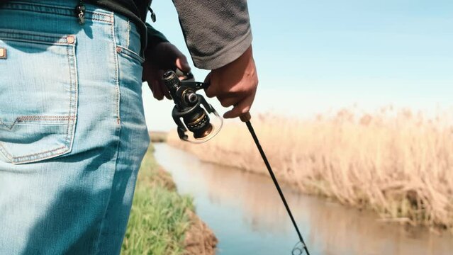  Close-up of the fisherman winding the line on the reel. Fishing in beautiful weather. . High quality 4k footage