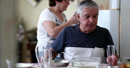 Fototapeta na wymiar Candid casual older couple at home during lunch time. Senior serving food into plate