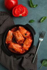 Stuffed cabbage rolls in tomato sauce, stuffed cabbage leaves, minced meat with rice, on a dark background, top view, no people,