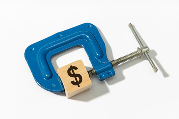 Monetary tightening policy concept. Financial pressure. Clamp compresses dollar sign on wooden block