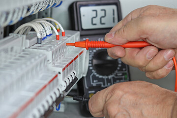A multimeter in the hands of an engineer with the parameters of the voltage of the electric current in close-up.