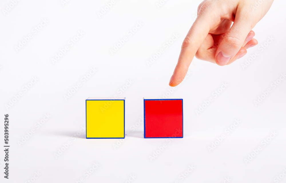 Poster choice concept. forefinger pointing to red cube instead of yellow one. making decision between two v