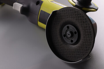 Electrical saw, grinder with nozzle on grey surface, detailed picture of powerful circular saw tool