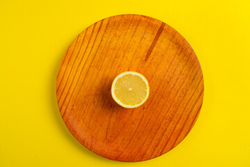 Top view of halved lemon on wooden plate isolated on yellow background, healthy food concept