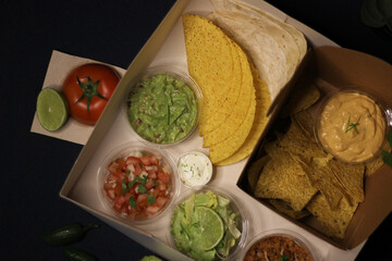 Mexican food box, tex mex, Taco, chili, tortilla, nachos chips, cheddar cheese, guacamole, sour cream, lettuce, tomato