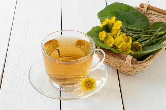 Herbal tea with coltsfoot, flowers and leaves in basket