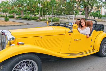 Beautiful woman in a yellow retro vintage convertible car